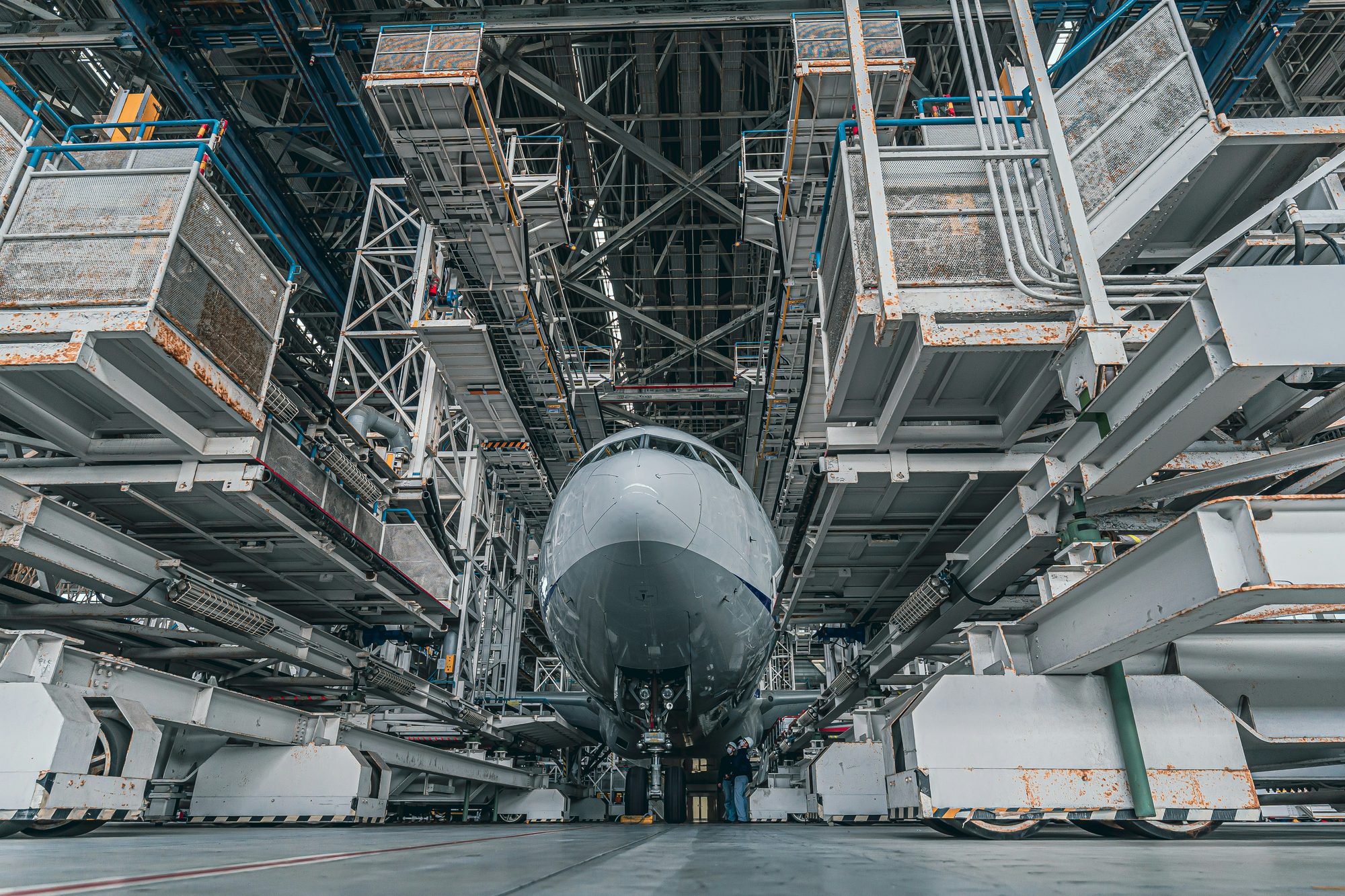 Aircraft in a heavy maintenance dock, engineers small against the machine